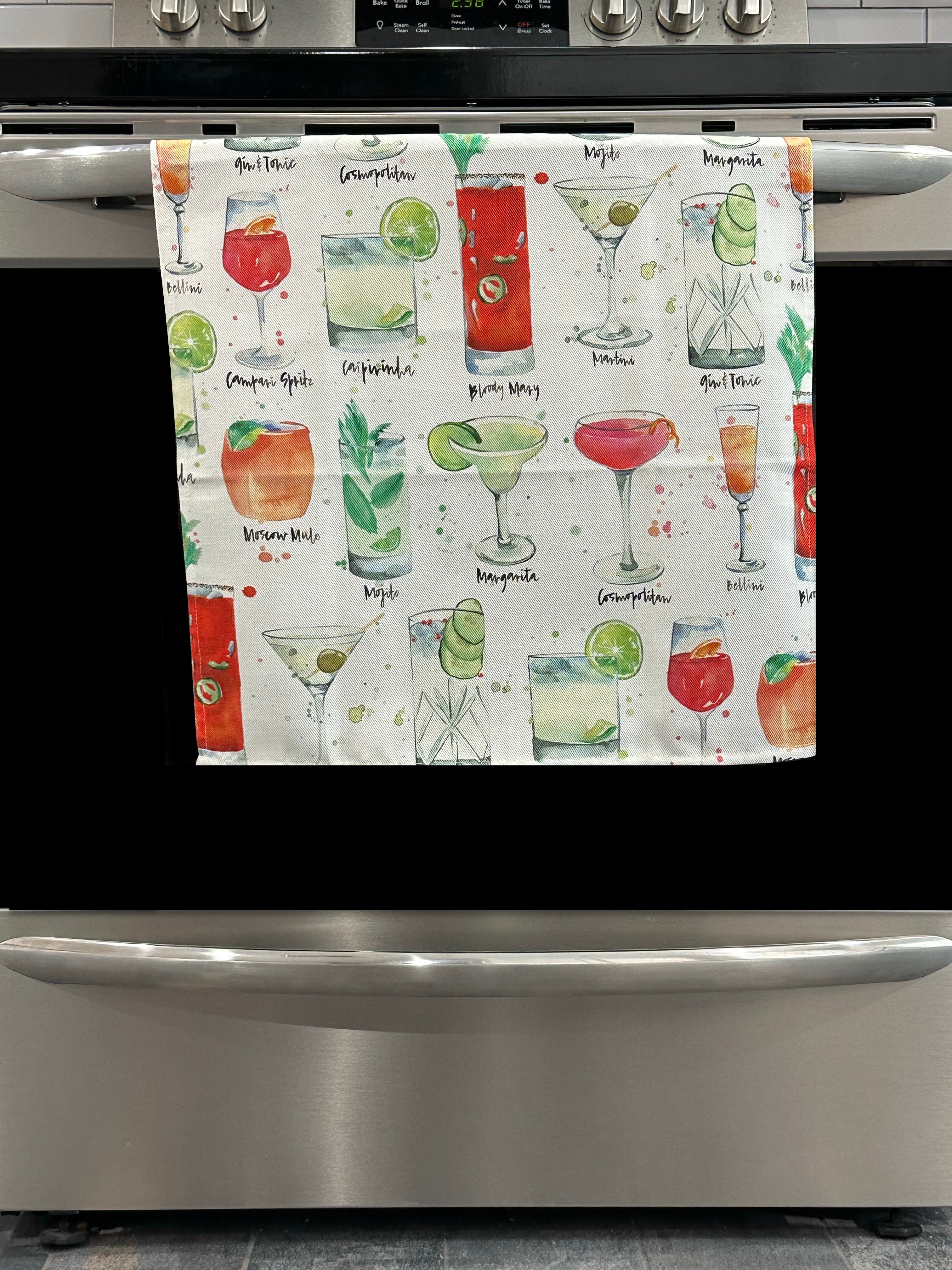 Kitchen Towel featuring a multicolor cocktails design. Pictured here hanging on a stove.