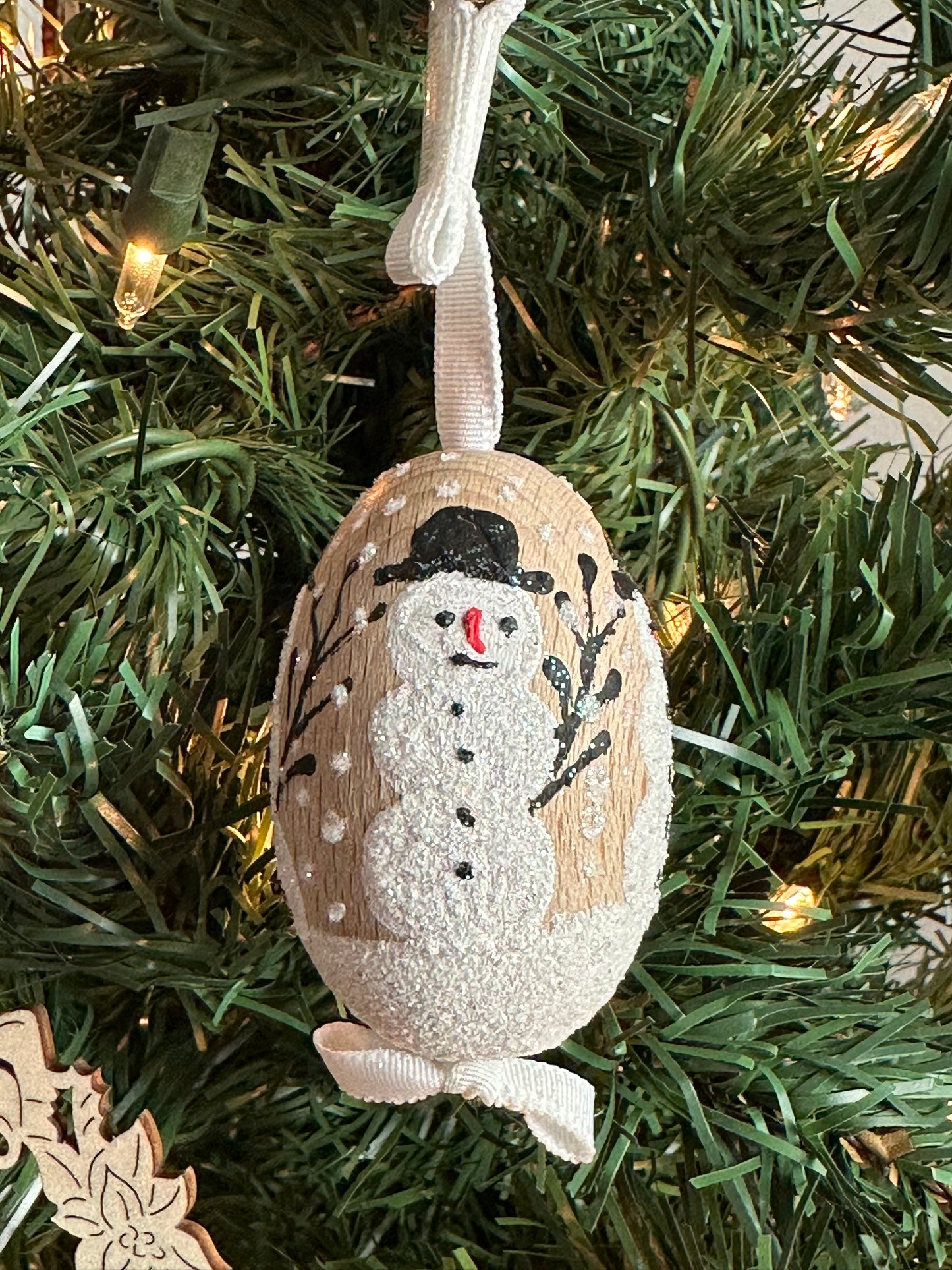 Austrian Christmas Egg Ornament featuring a glittery snowman design, hanging on a tree.