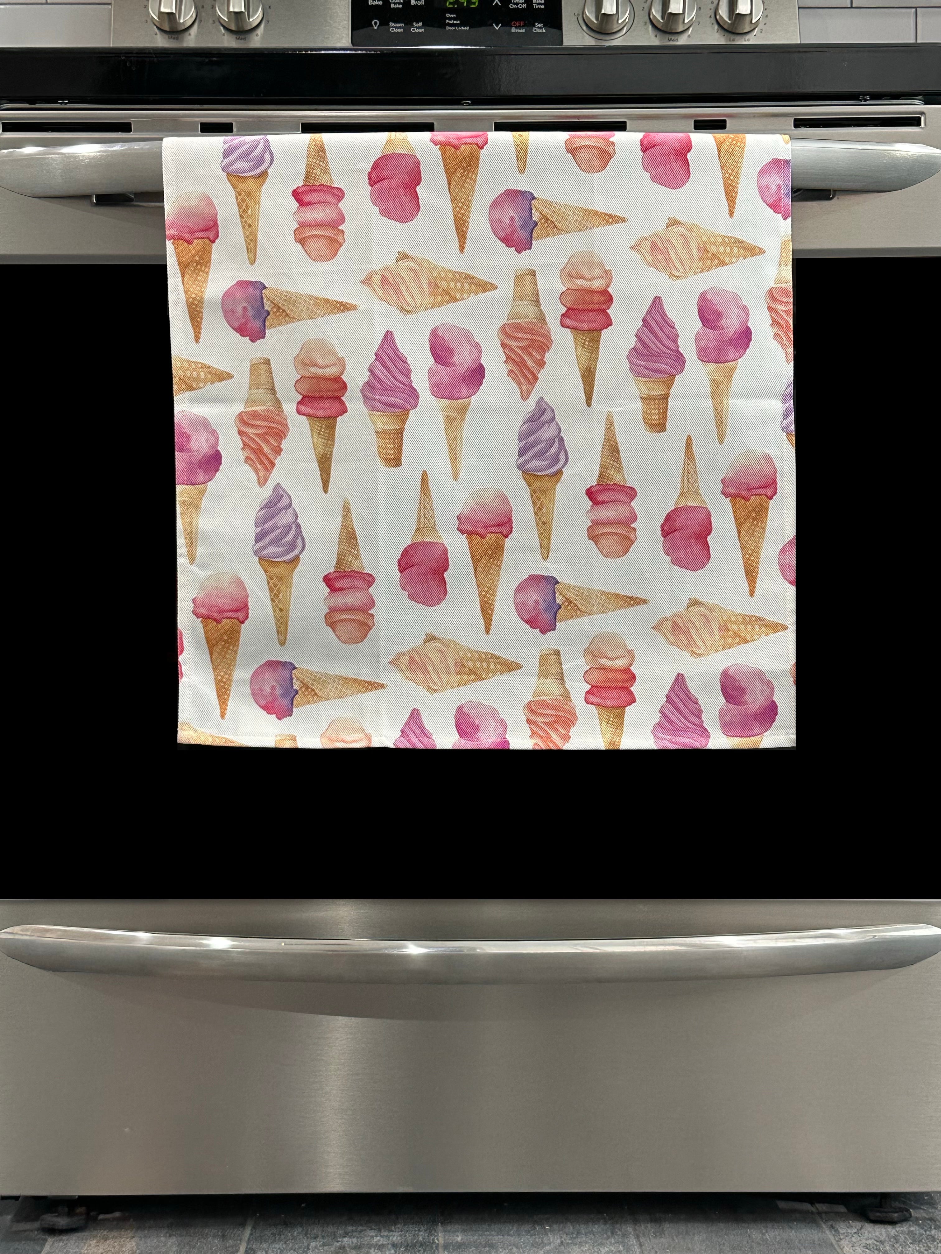 Kitchen Towel featuring a pastel ice cream cone design. Pictured here hanging on a stove.