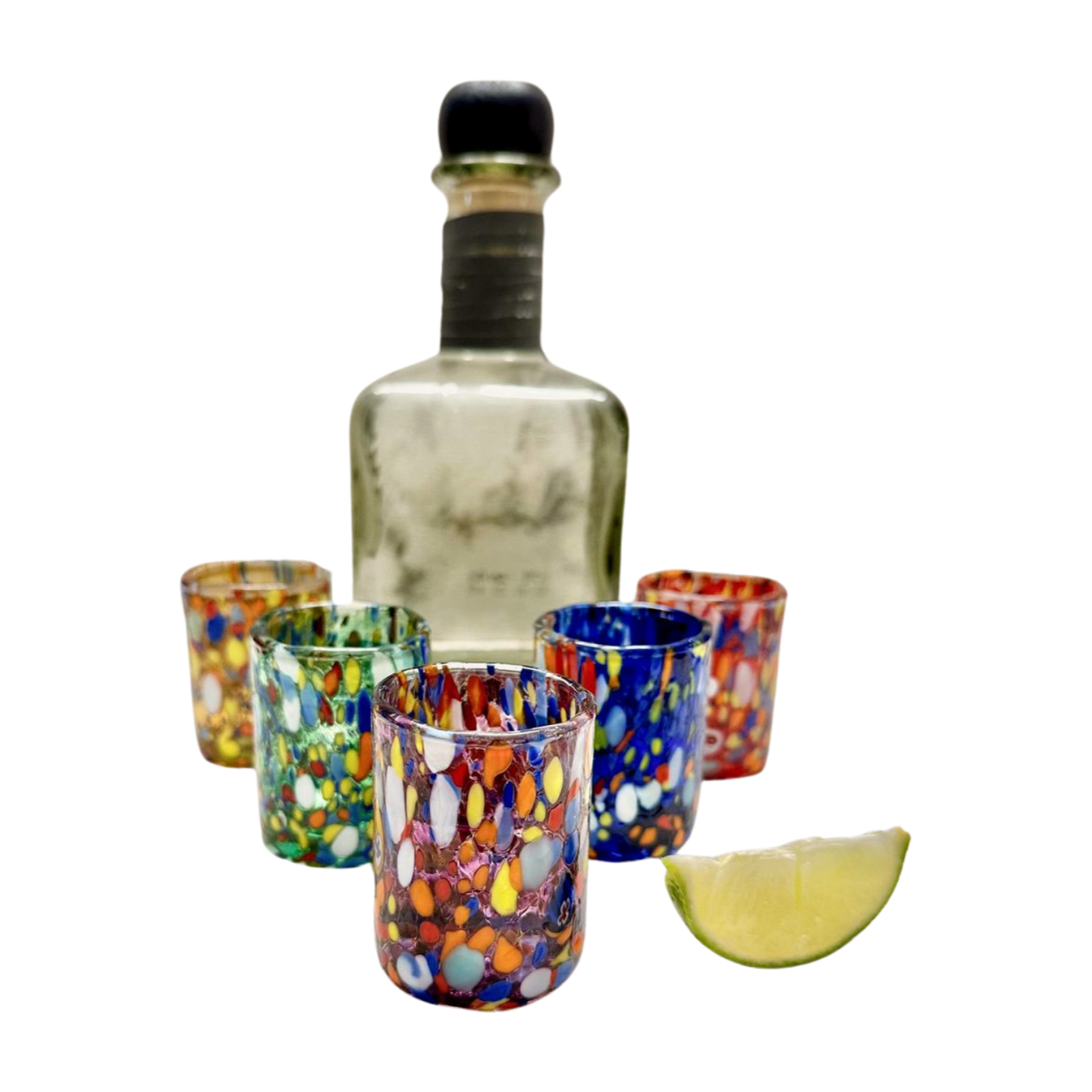 Murano glass shot glasses show with a bottle of tequila and a sliced lime.