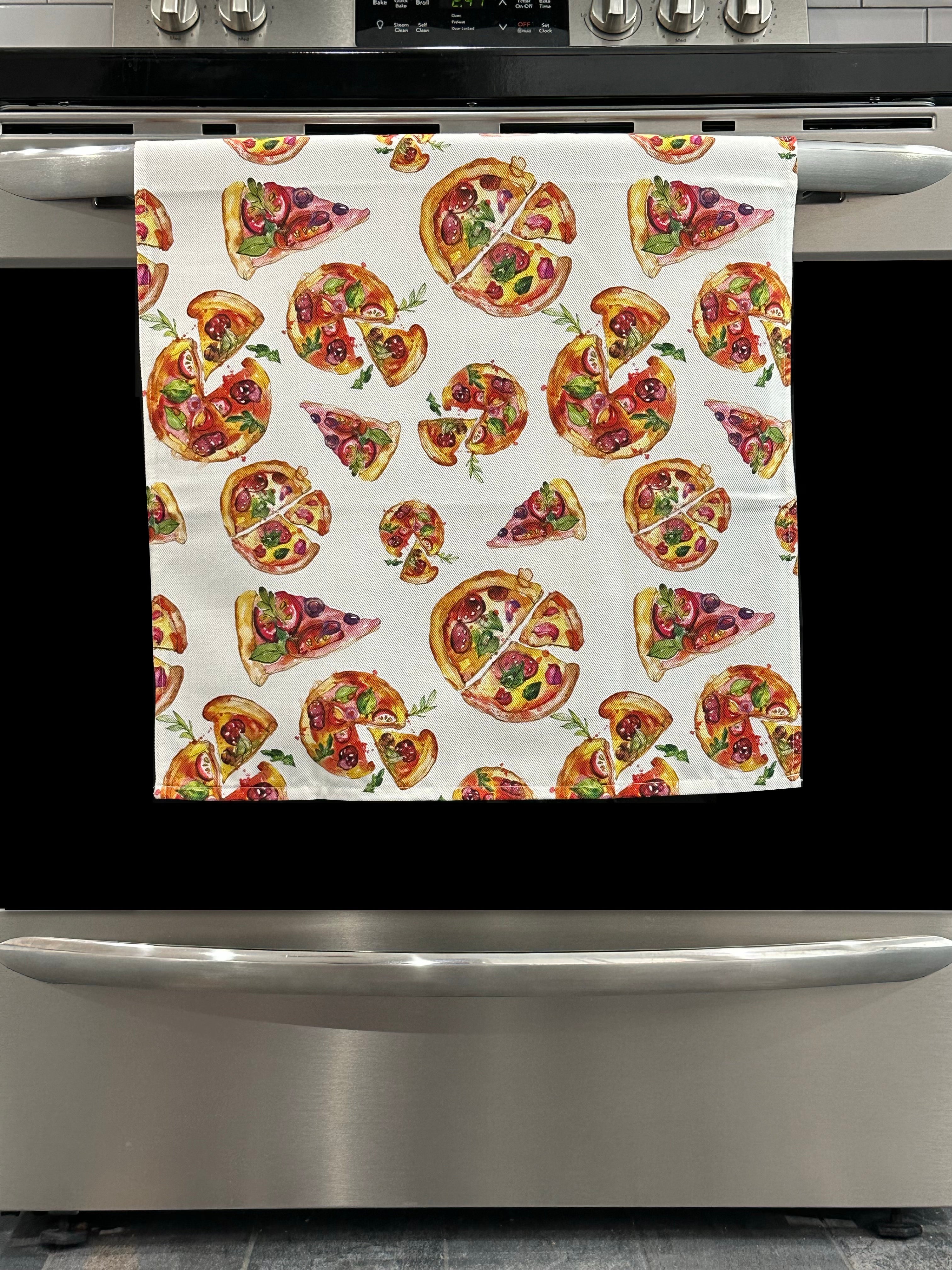 Kitchen Towel featuring a multicolor pizza design. Pictured here hanging on a stove.